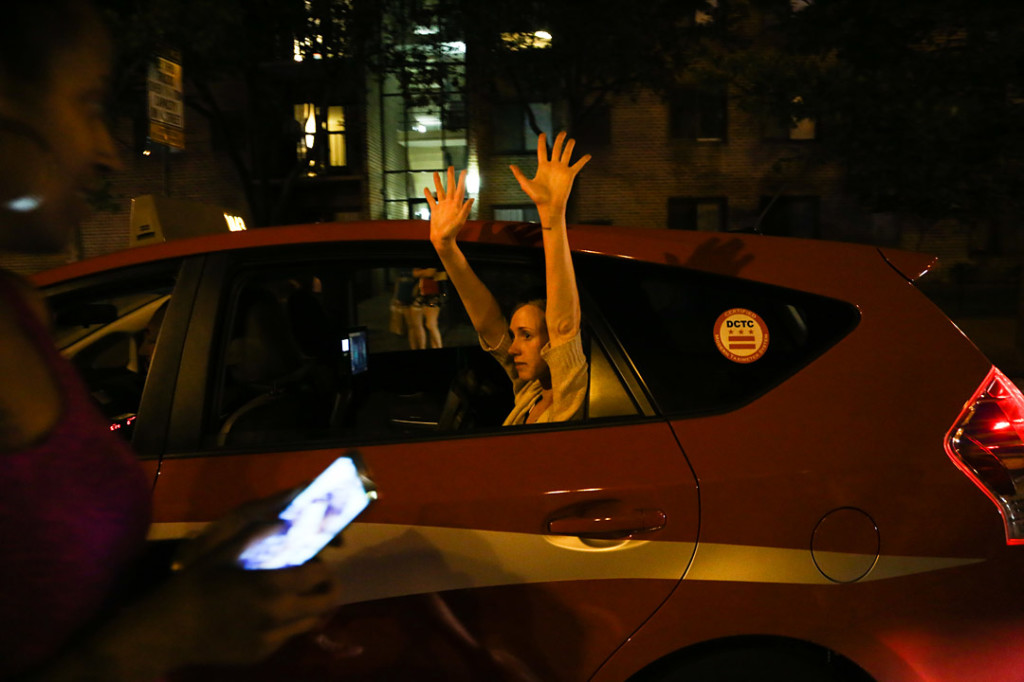 A woman in a cab holds up her hands in solidarity with the marchers after the National Moment of Silence for Michael Brown on Thursday, August 14, 2014 in Washington D.C. Protesters held a moment of silence for Michael Brown who was shot by police in Ferguson, Missouri. Brown was unarmed and had his hands up at the time he was shot. Photo credit: Brian Nguyen