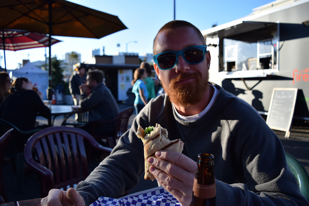 Sam Woods, 29, of San Francisco, takes a bite out of dinner at SoMa StrEat Food Park on Tuesday, August 11, 2015.